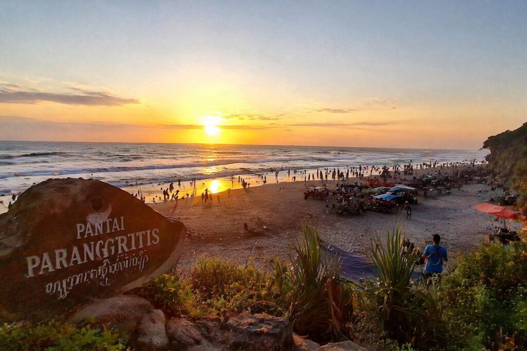 Pantai Parangtritis Jogja saat sunset dengan pemandangan ombak dan wisatawan di tepi pantai